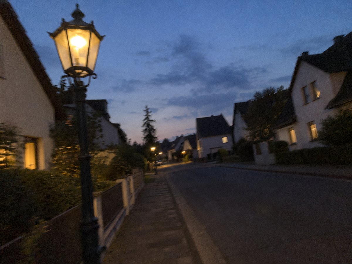Alte gusseiserne Gaslaterne in einer ruhigen Wohnstraße zur blauen Stunde.